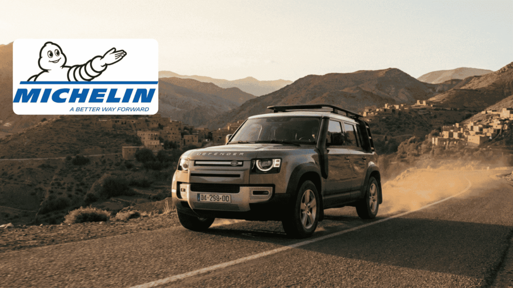 Un 4x4 Land Rover équipé de pneus Michelin roulant sur une route sinueuse dans les montagnes de l'Atlas au Maroc, avec le logo Michelin officiel.